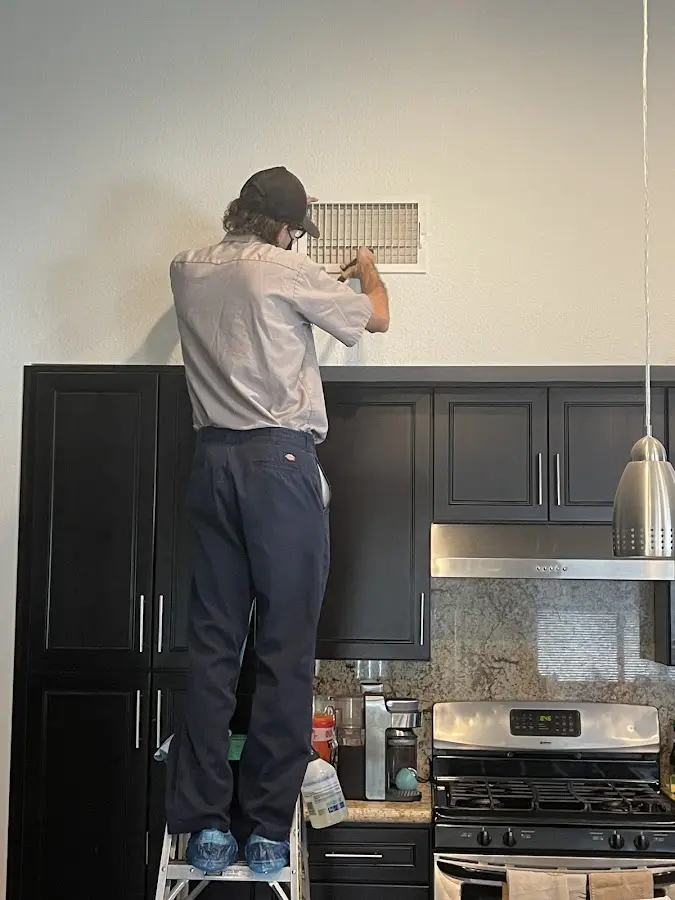 Technician inspecting an air vent during HVAC service in Cerritos